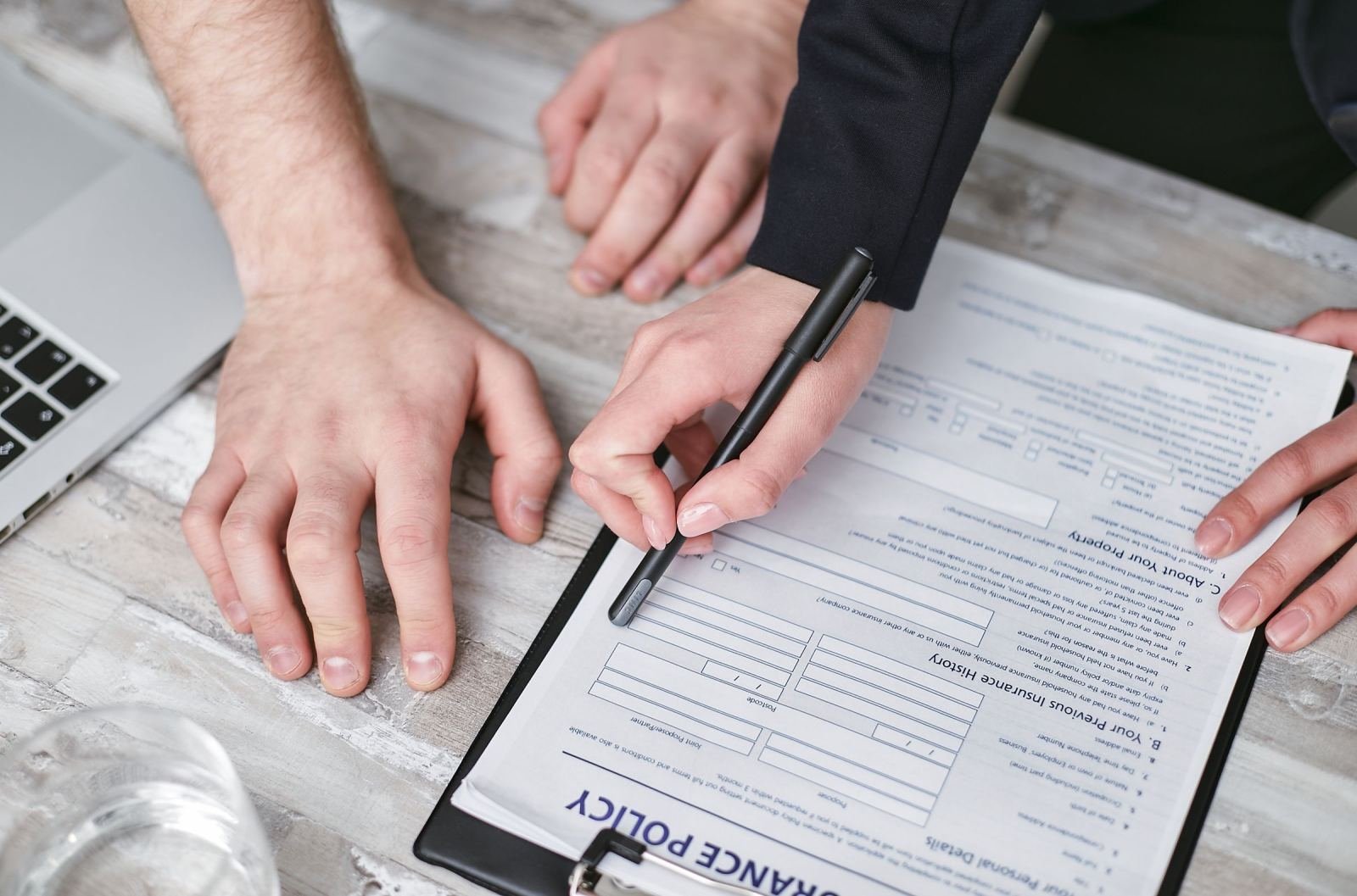 A person points a pen at an insurance policy document on a clipboard