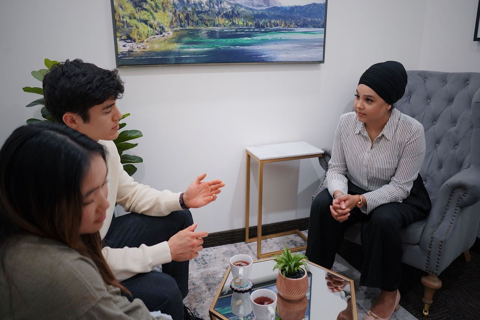 A woman in a turban listens to a couple in a bright office setting