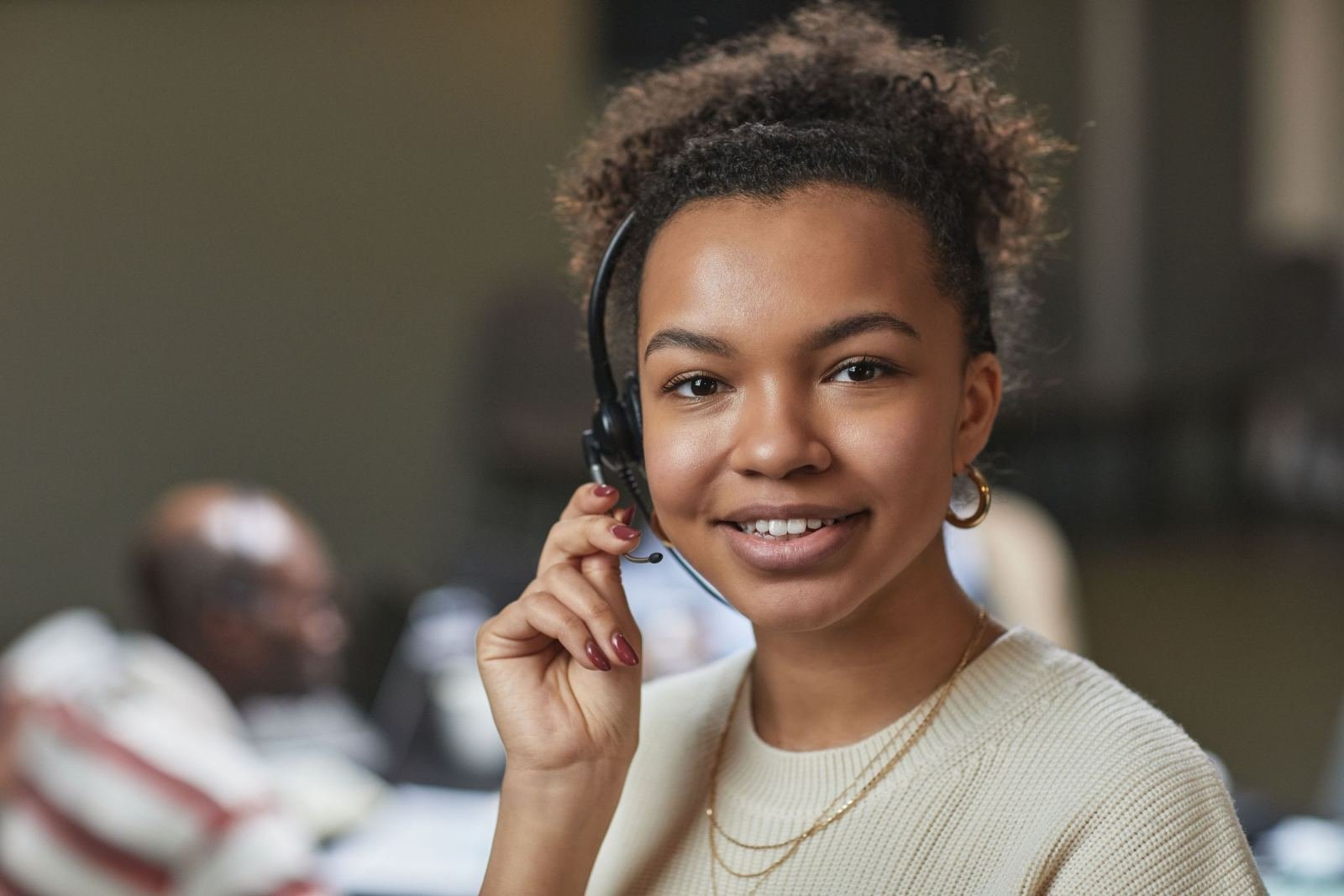 A woman wearing a headset smiles while working in an office