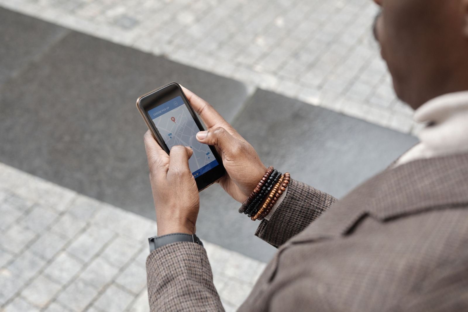 Someone holds a phone outside. They use a map app on the screen.