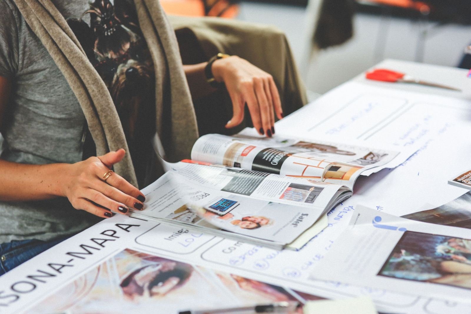 A woman reviews printed brochures and documents at a white table