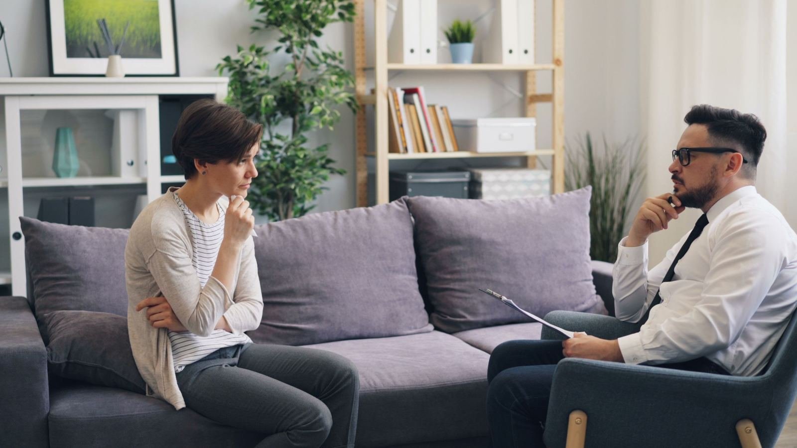 A woman and a man with a clipboard talk in a bright office