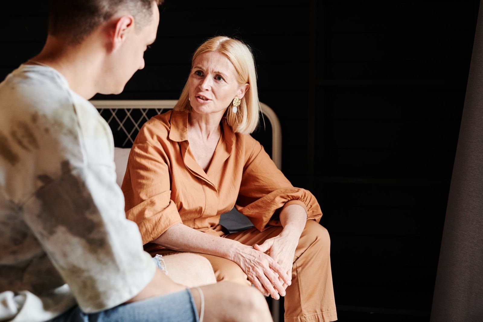 A woman in orange clothing talks to a man in a tie-dye shirt