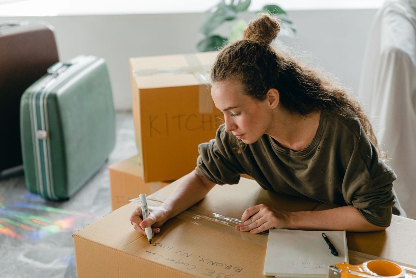 A woman writes on a cardboard box while packing for a move