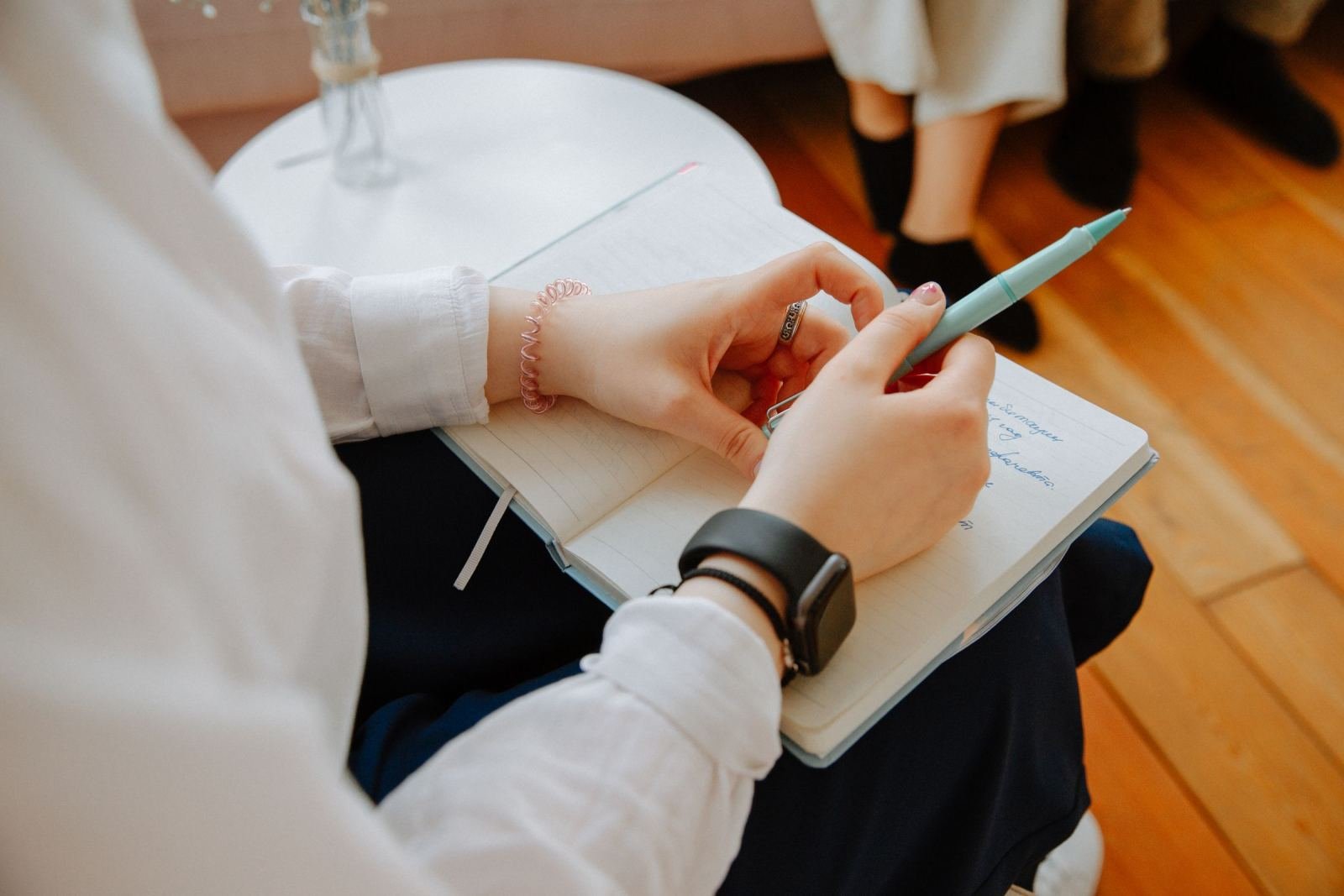 A person writes in a notebook with a blue pen during a session.