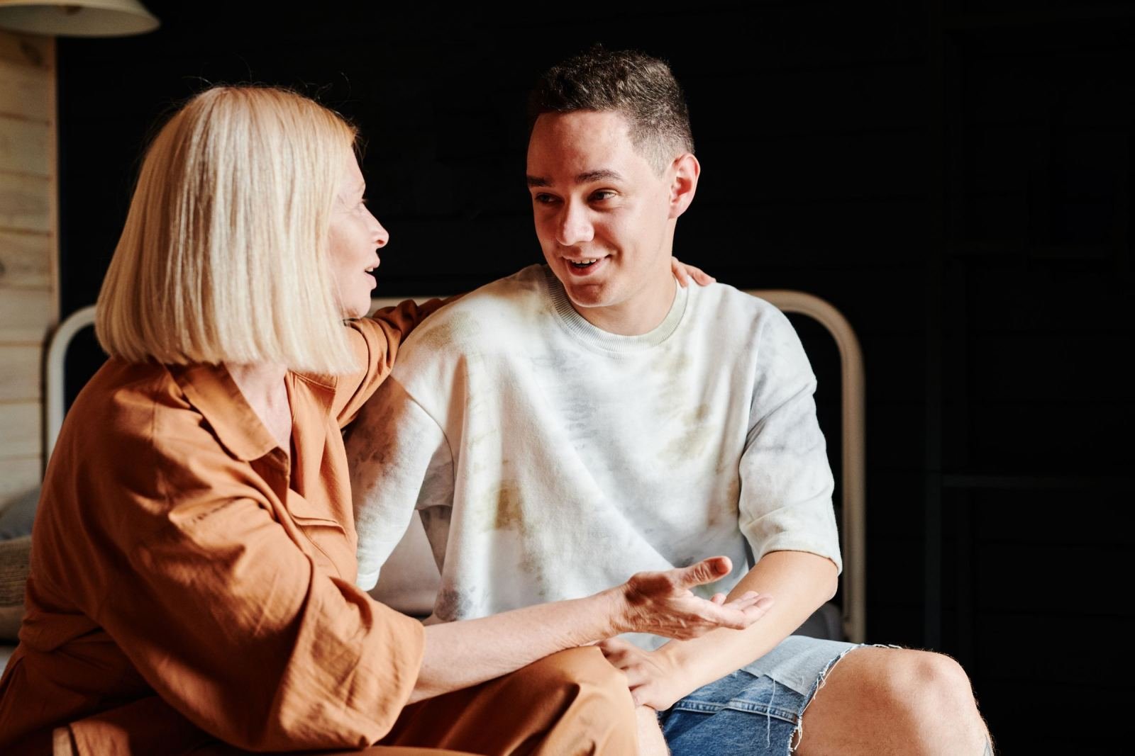 A woman talks to a man while resting her hand on his shoulder