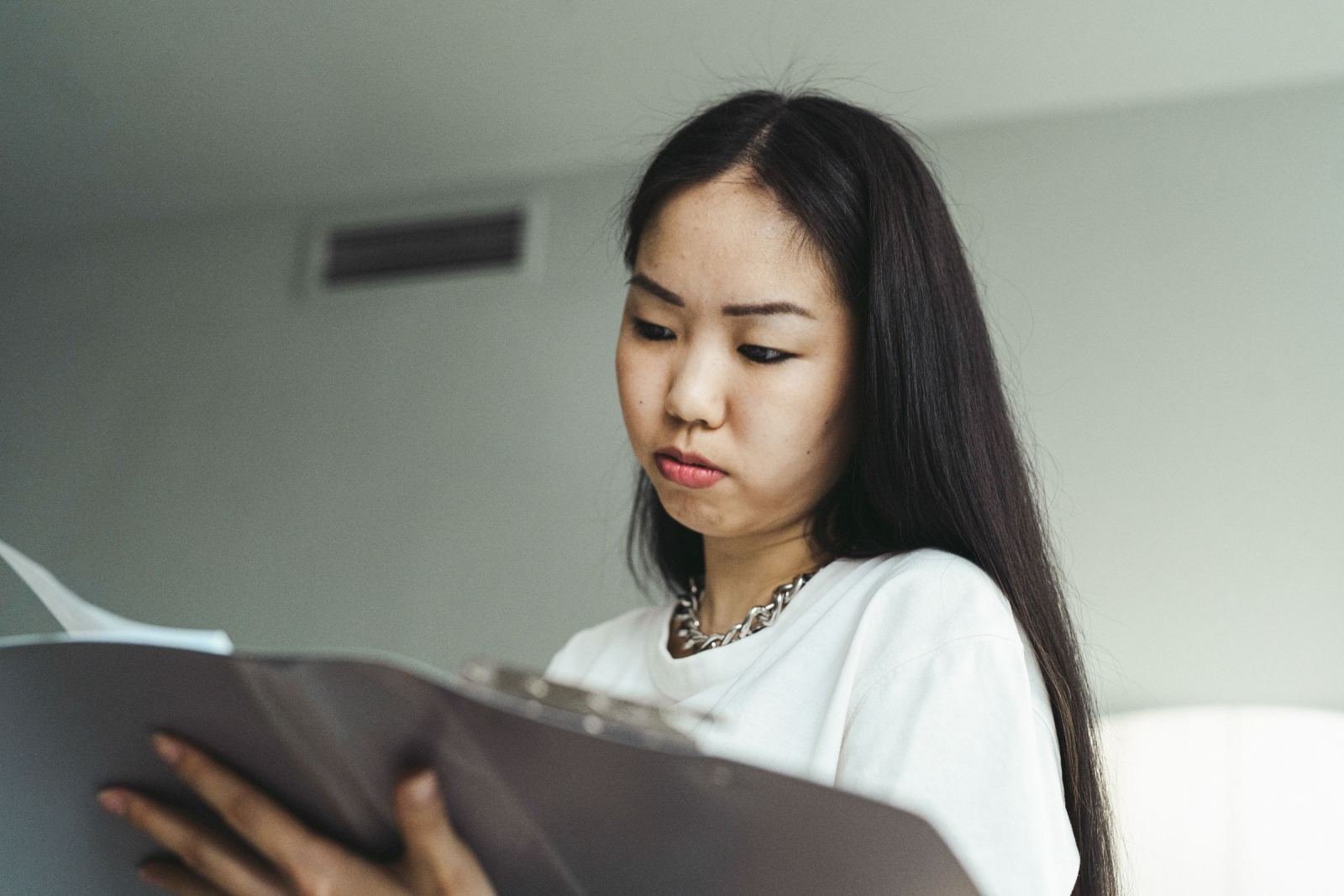 A woman with a serious look stares down at a folder she holds.