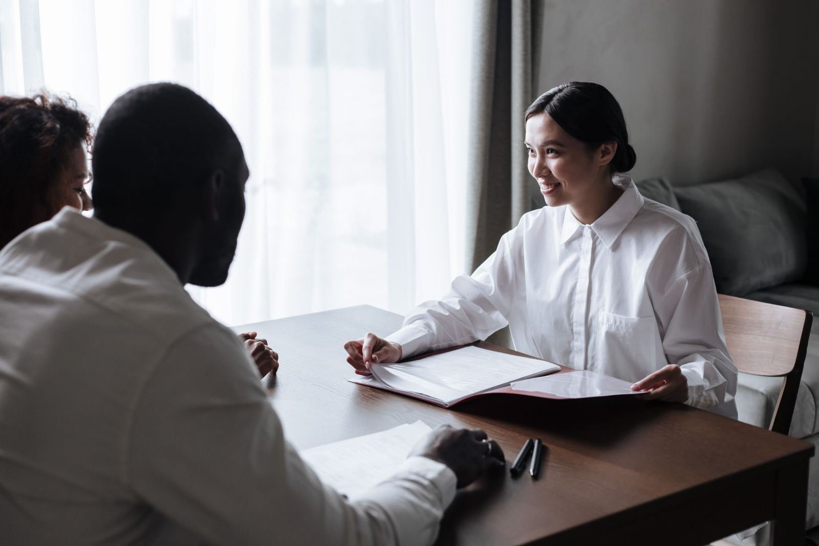A woman in a white shirt reviews a printed document with two other people at a table