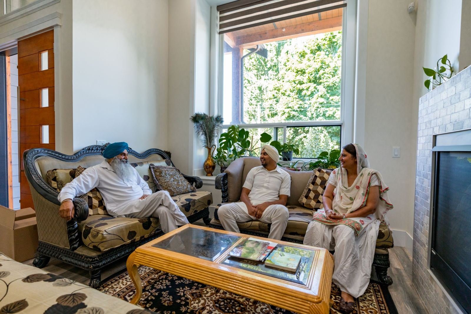 Image of three relatives in white clothes chatting in a sunny living room