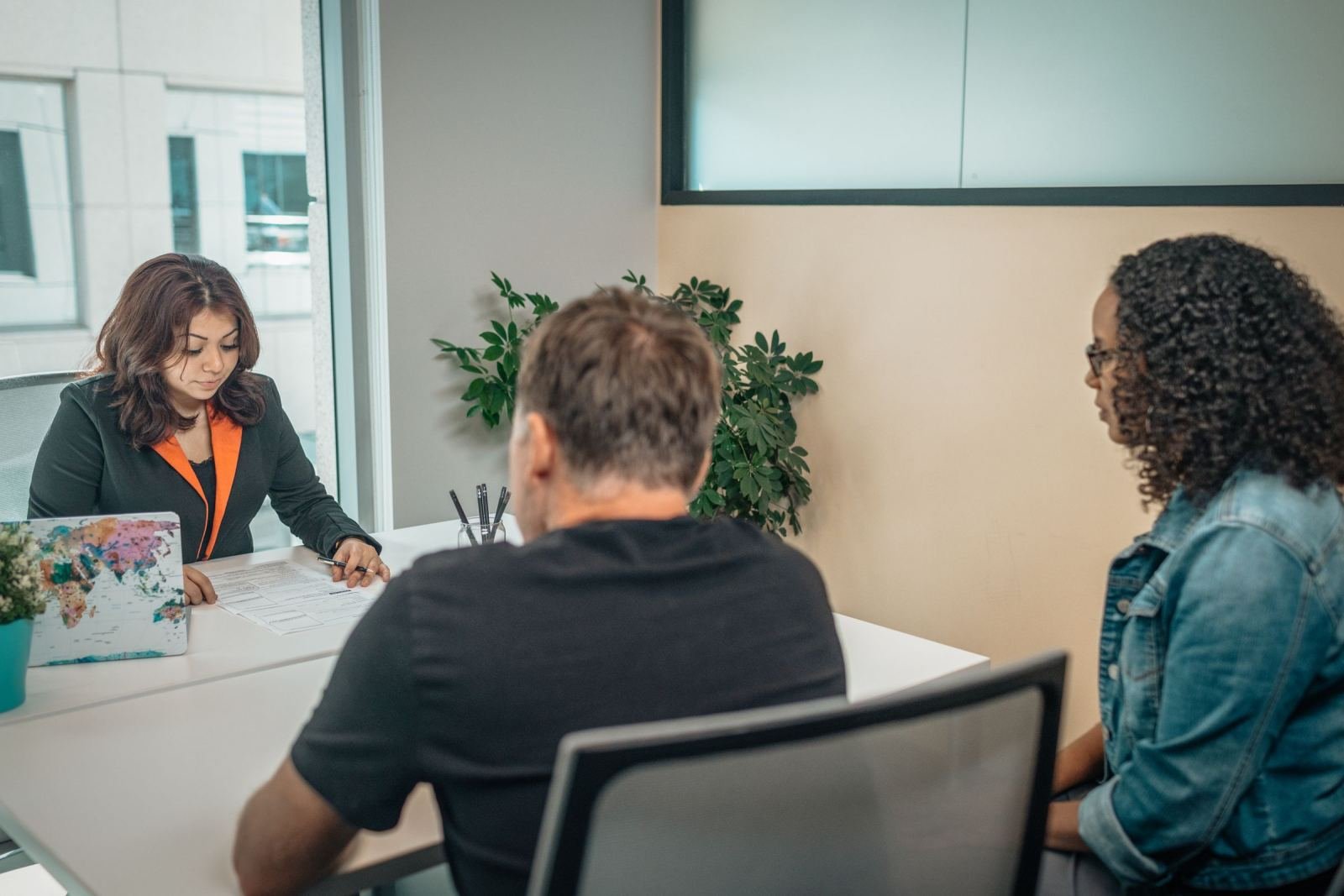 A provider and two clients review a printed form together at a white desk