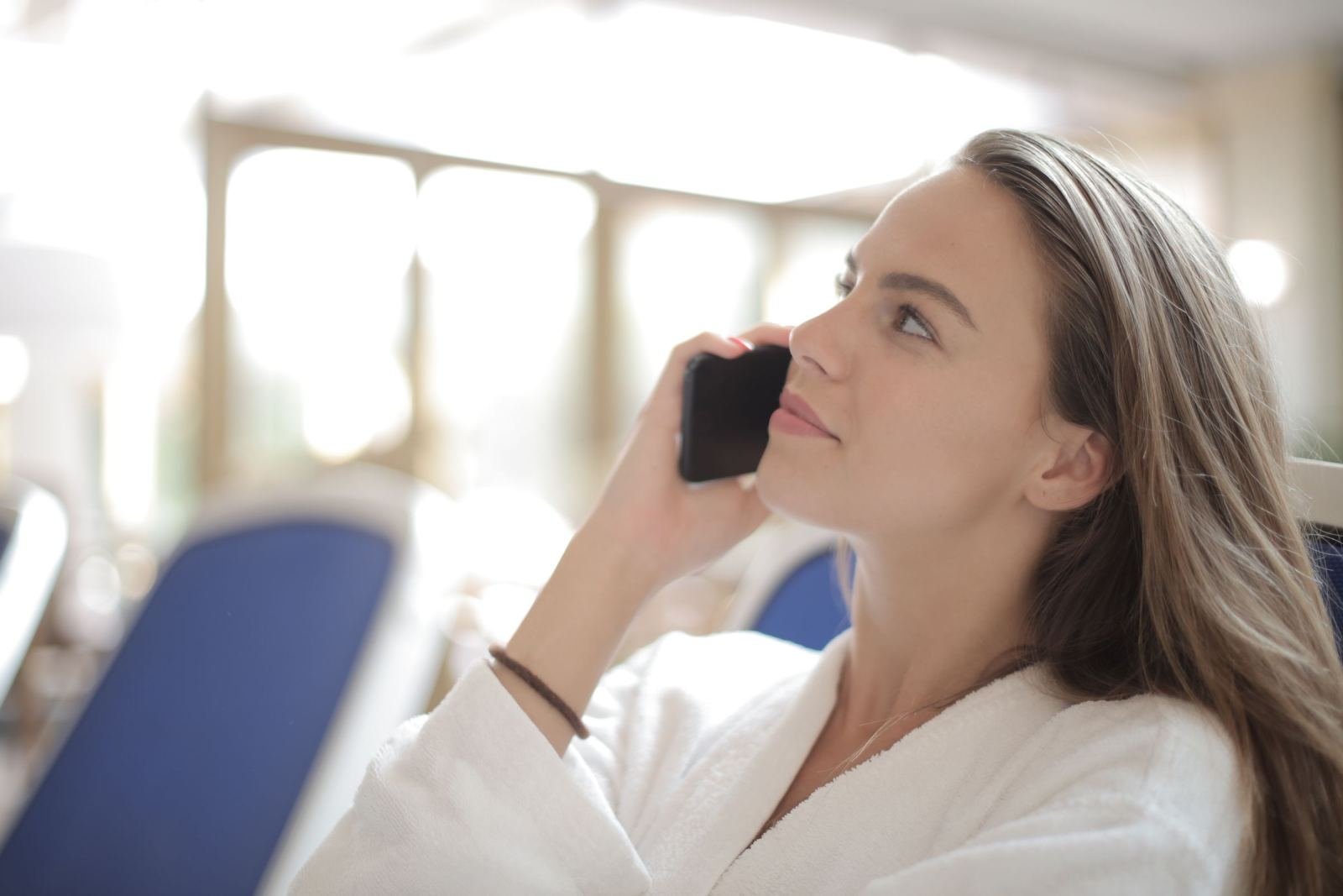 A woman in a white bathrobe talks on a smartphone