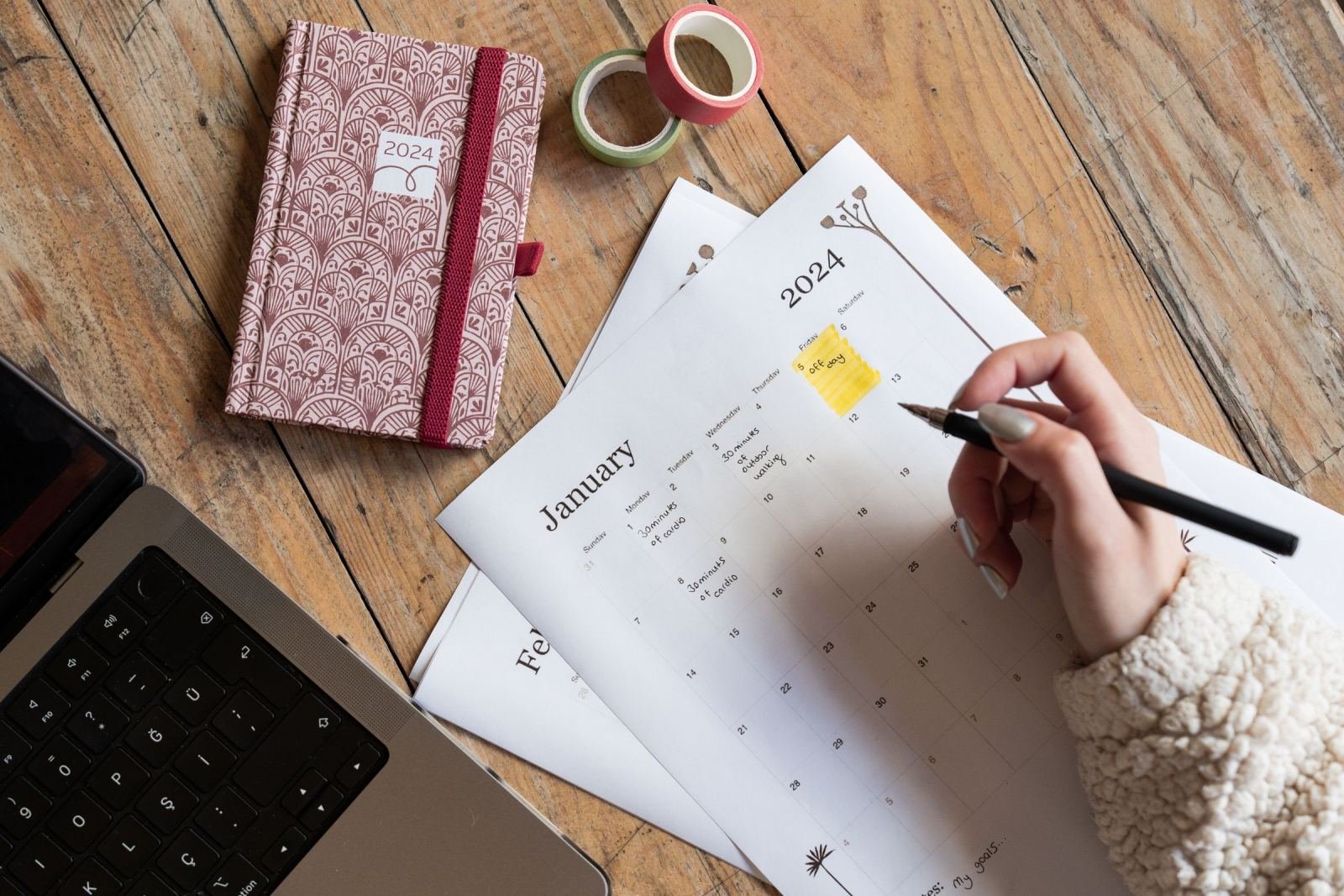 A person uses a pen to mark a date on a 2024 January calendar