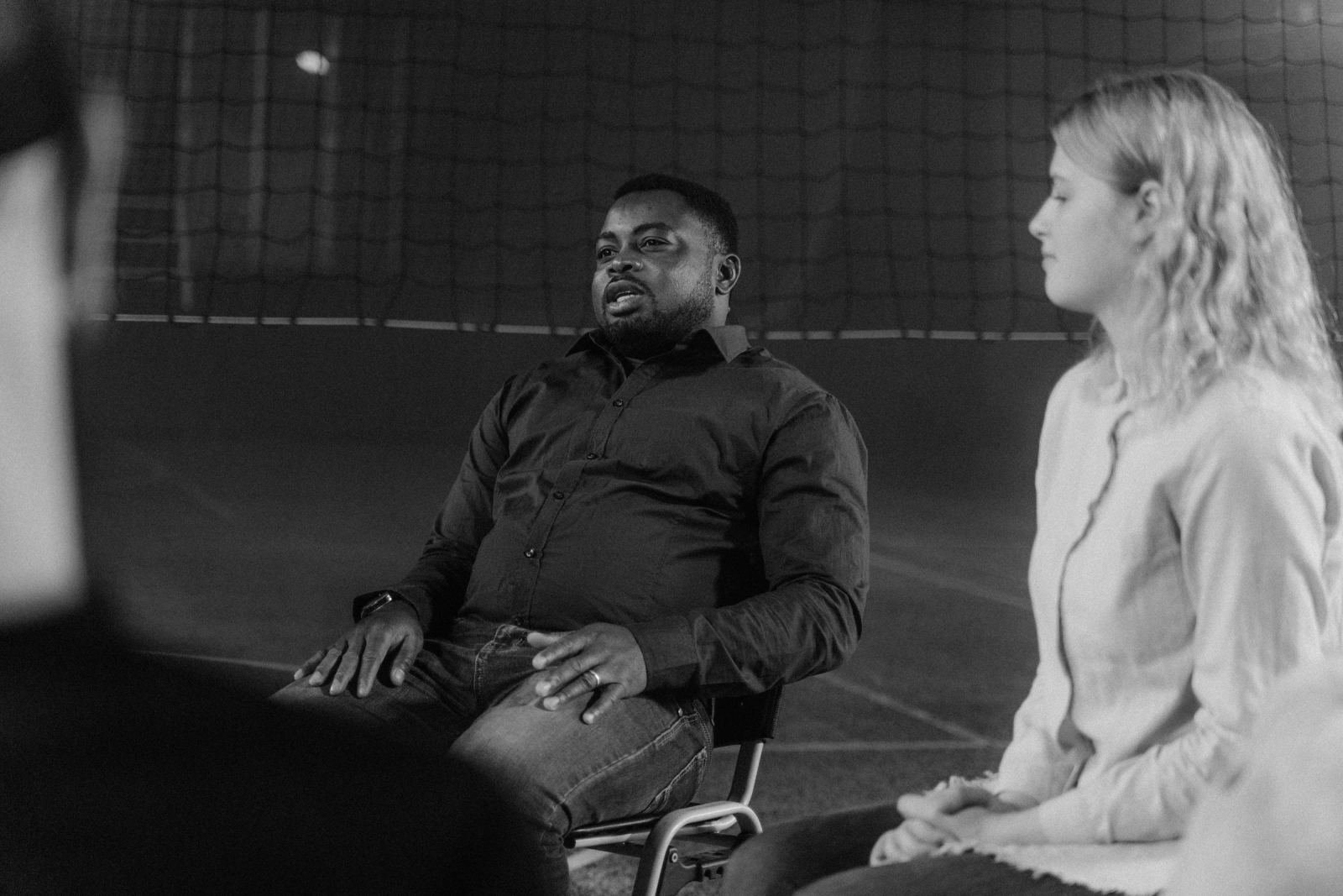 A man and woman sit in a circle and listen to a group discussion