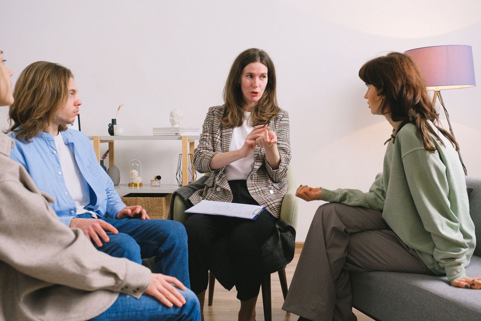 A counselor with a clipboard speaks with two adults in a bright room