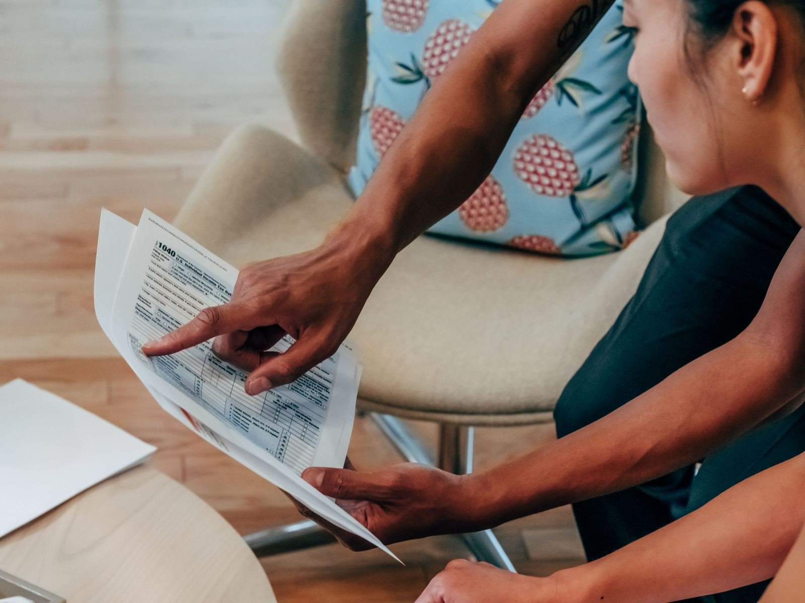 A person points to a printed document while reviewing it with another person