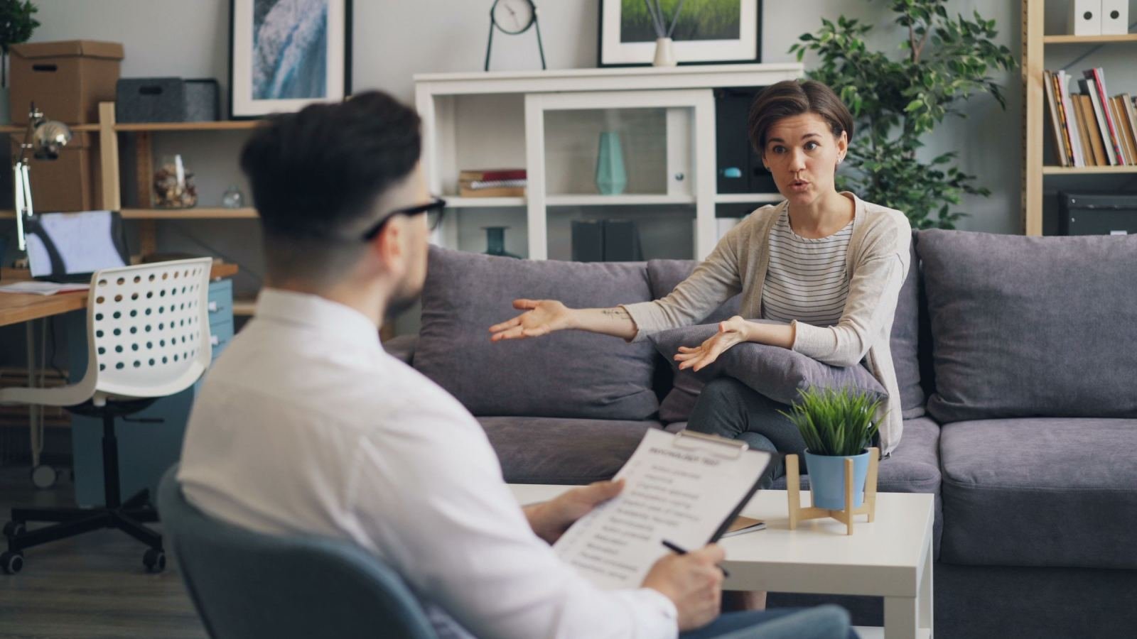 A woman gestures while speaking to a counselor holding a clipboard
