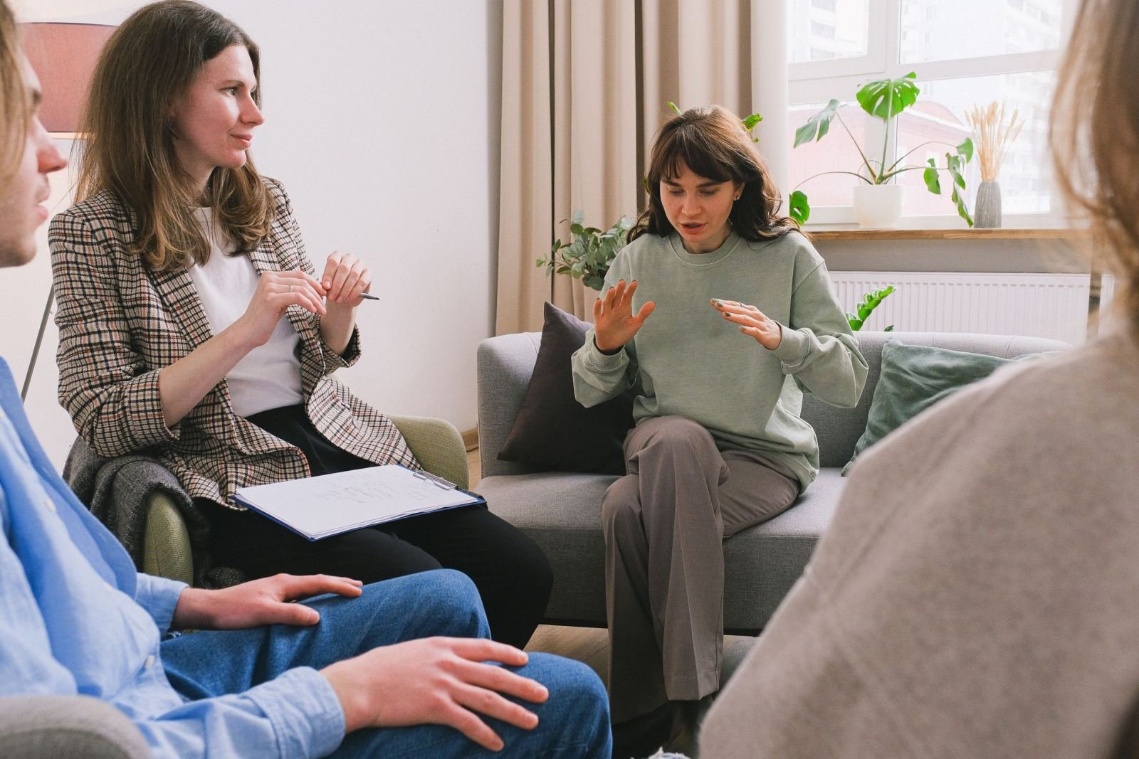 A group of adults in a circle during a therapy session with a facilitator