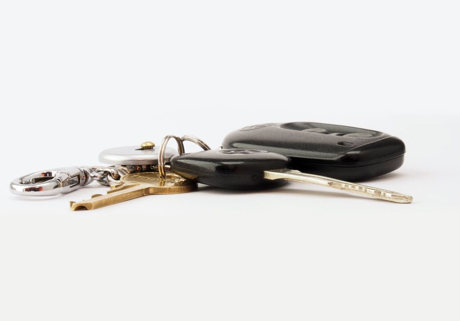 A set of car keys and a black key fob on a white surface