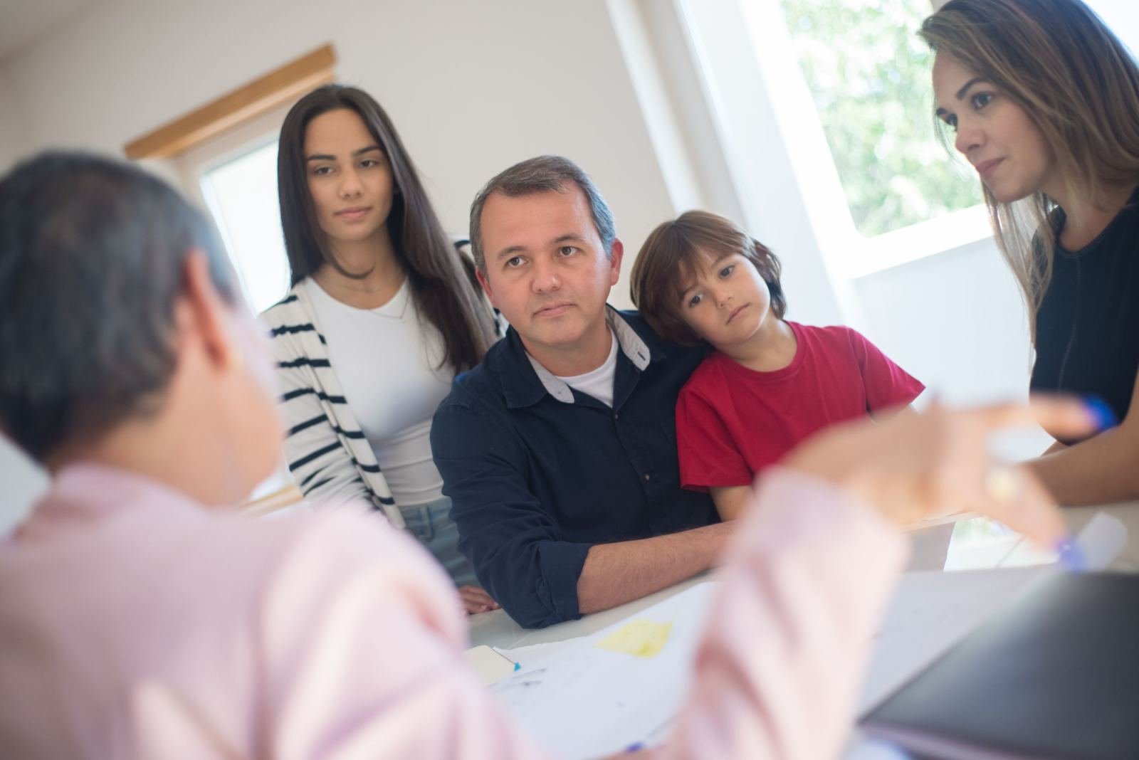 A family of three listens to a professional in a bright office