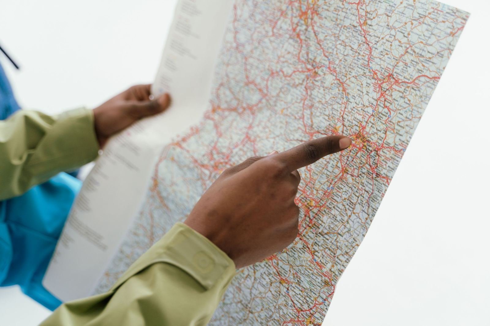 A person pointing to a location on a paper road map