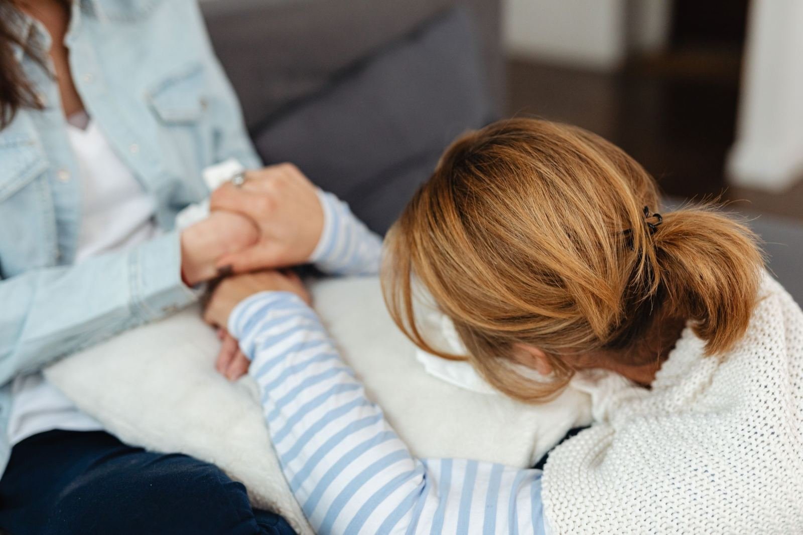A person holds hands with someone resting on a white pillow