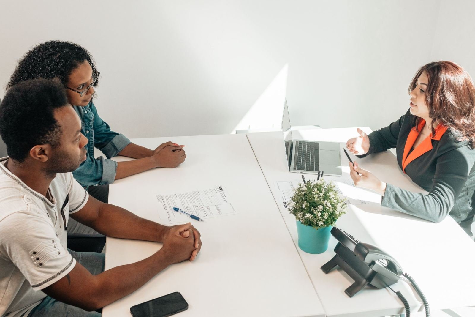 A couple meets with a professional woman in an office setting