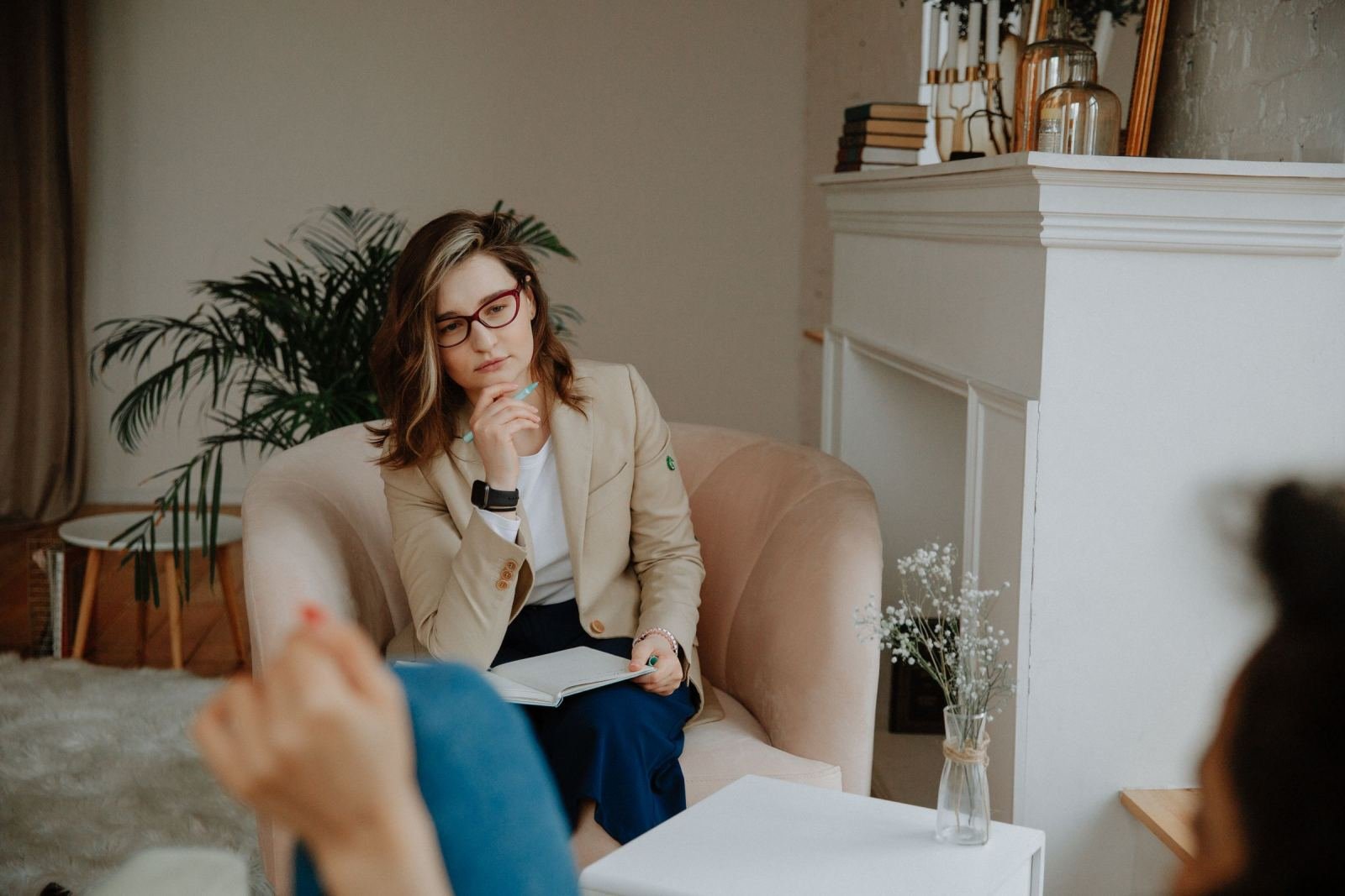 A professional woman with a notebook listens to a client in a welcoming office