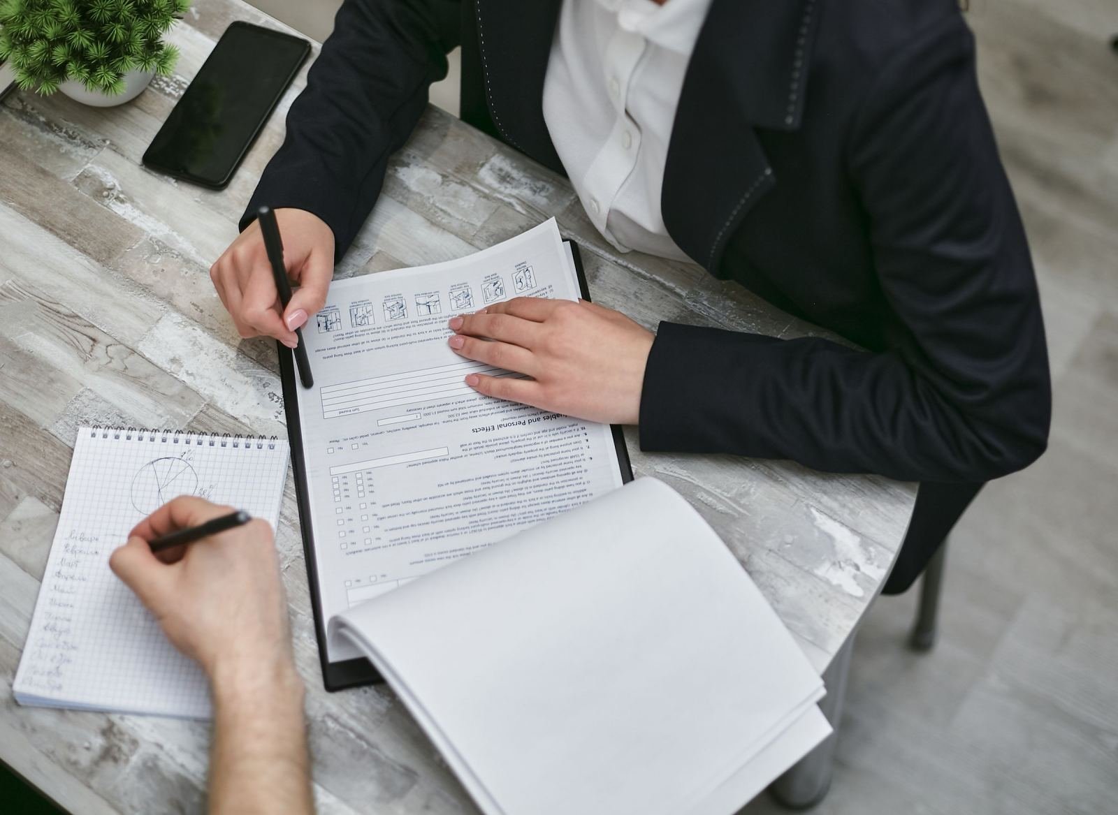 Two people reviewing documents and taking notes at a desk