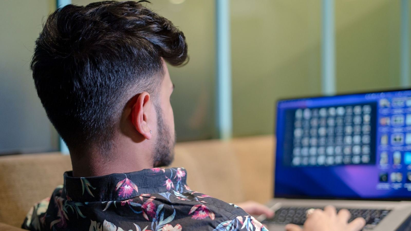 A man in a floral shirt using a laptop