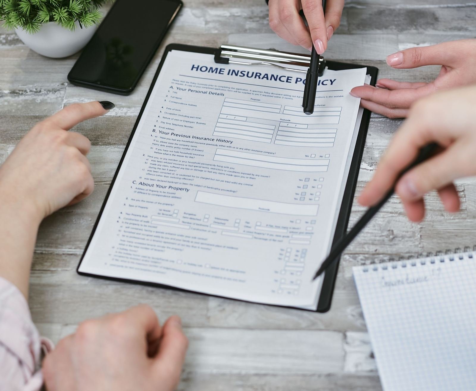 Two people review a home insurance policy document on a clipboard