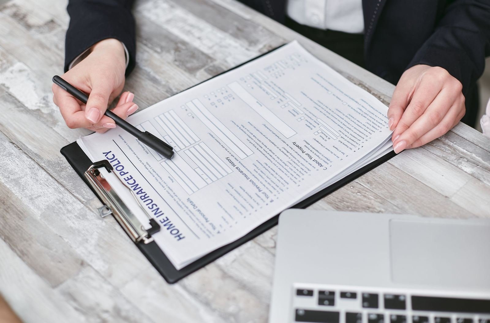 A person in a blazer points to a home insurance policy document on a clipboard