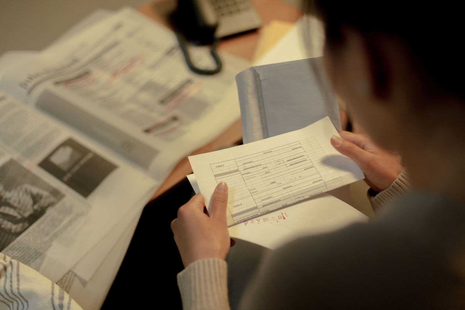 A person holds and reviews a printed form at a desk