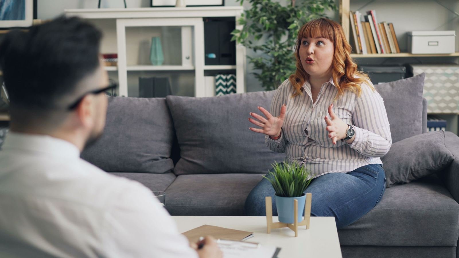 A woman gestures while speaking to a man in a modern office setting