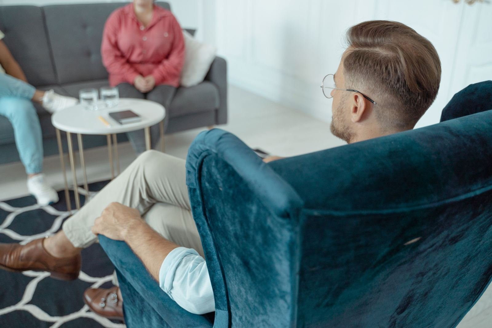 In a bright office, a man and woman face each other while sitting in chairs.