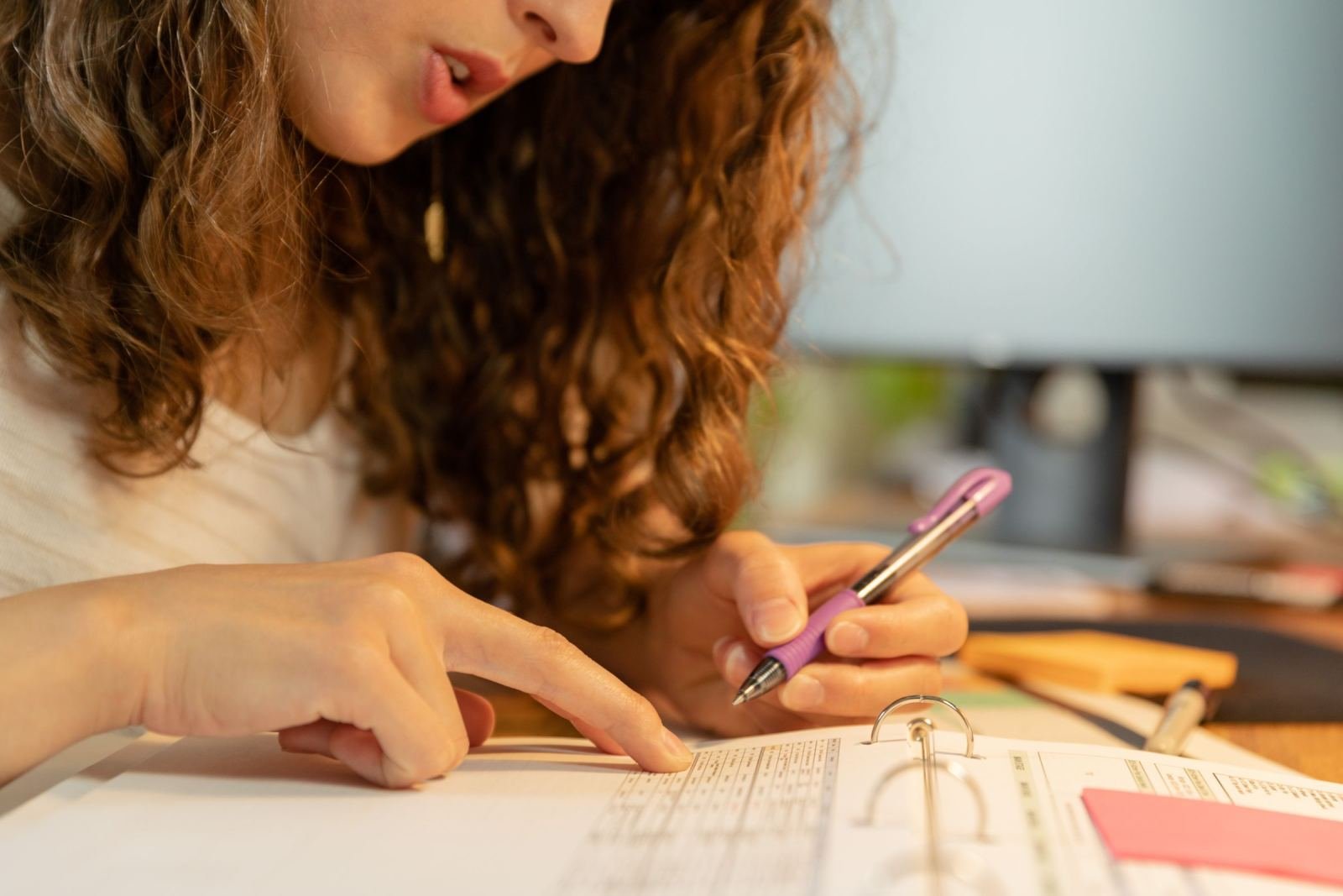 A person points to a line on a document while holding a purple pen