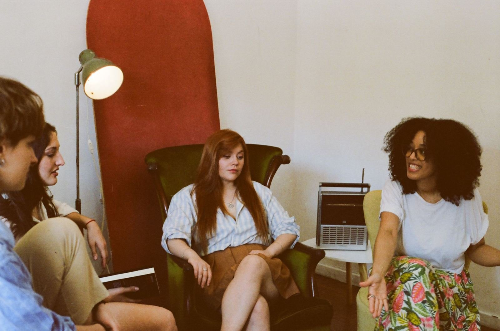 In a well-lit room, three women form a circle to chat.