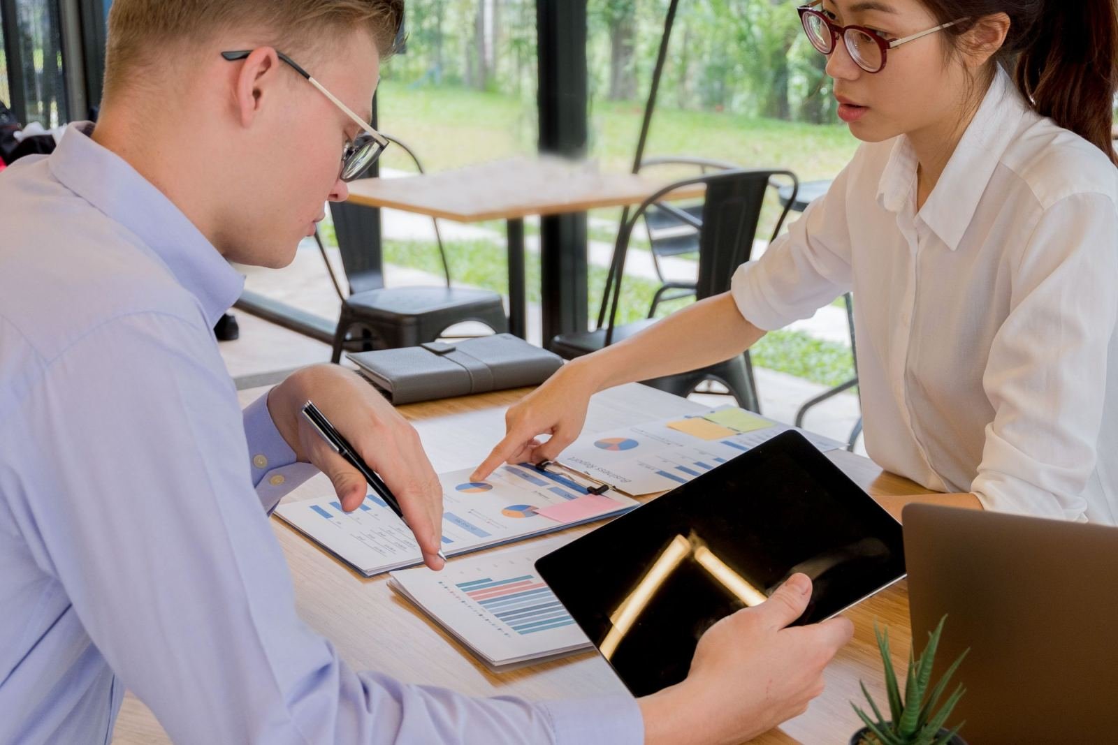 A man and woman review financial documents and charts at a desk