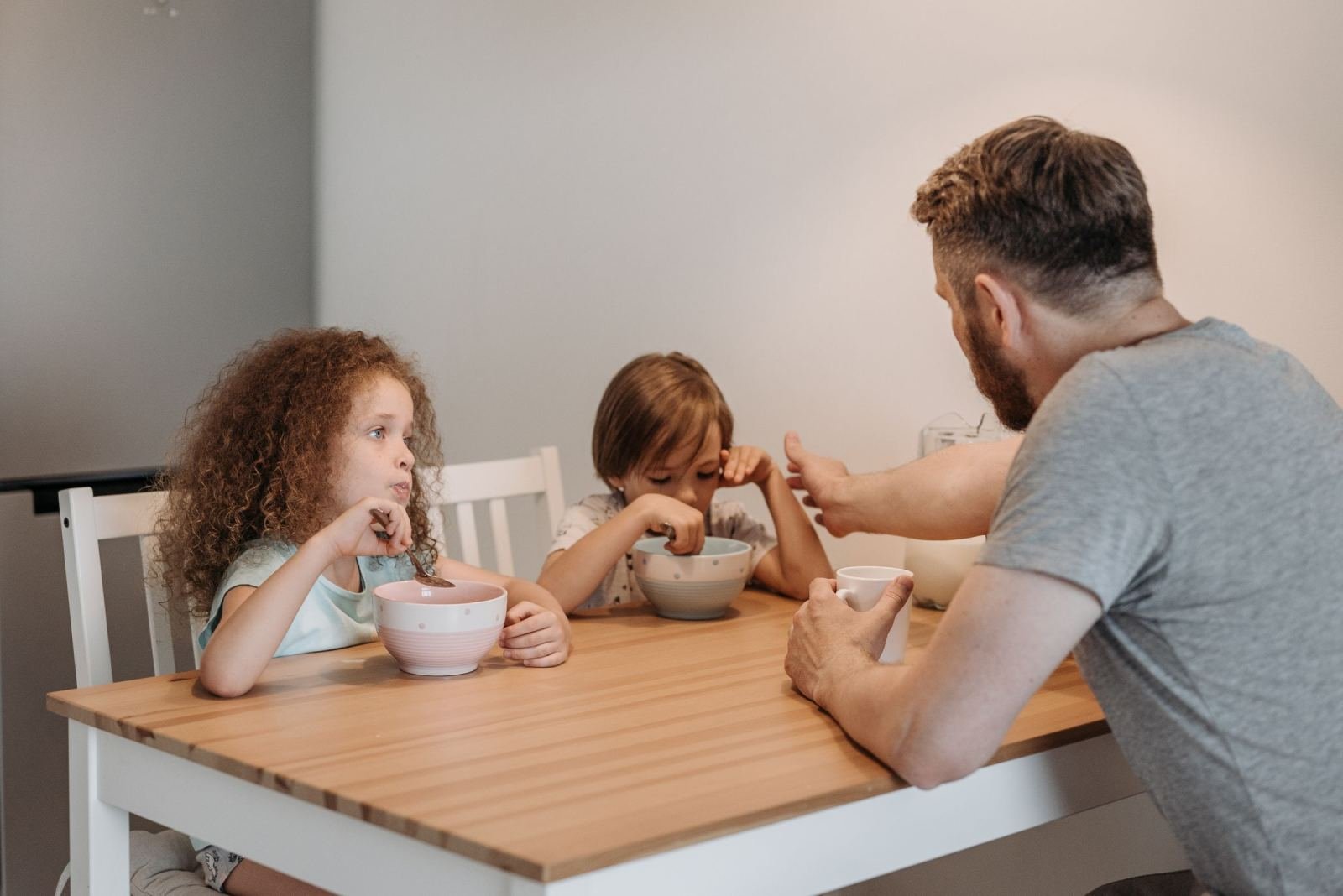 A man and two children eating breakfast together at a wooden table