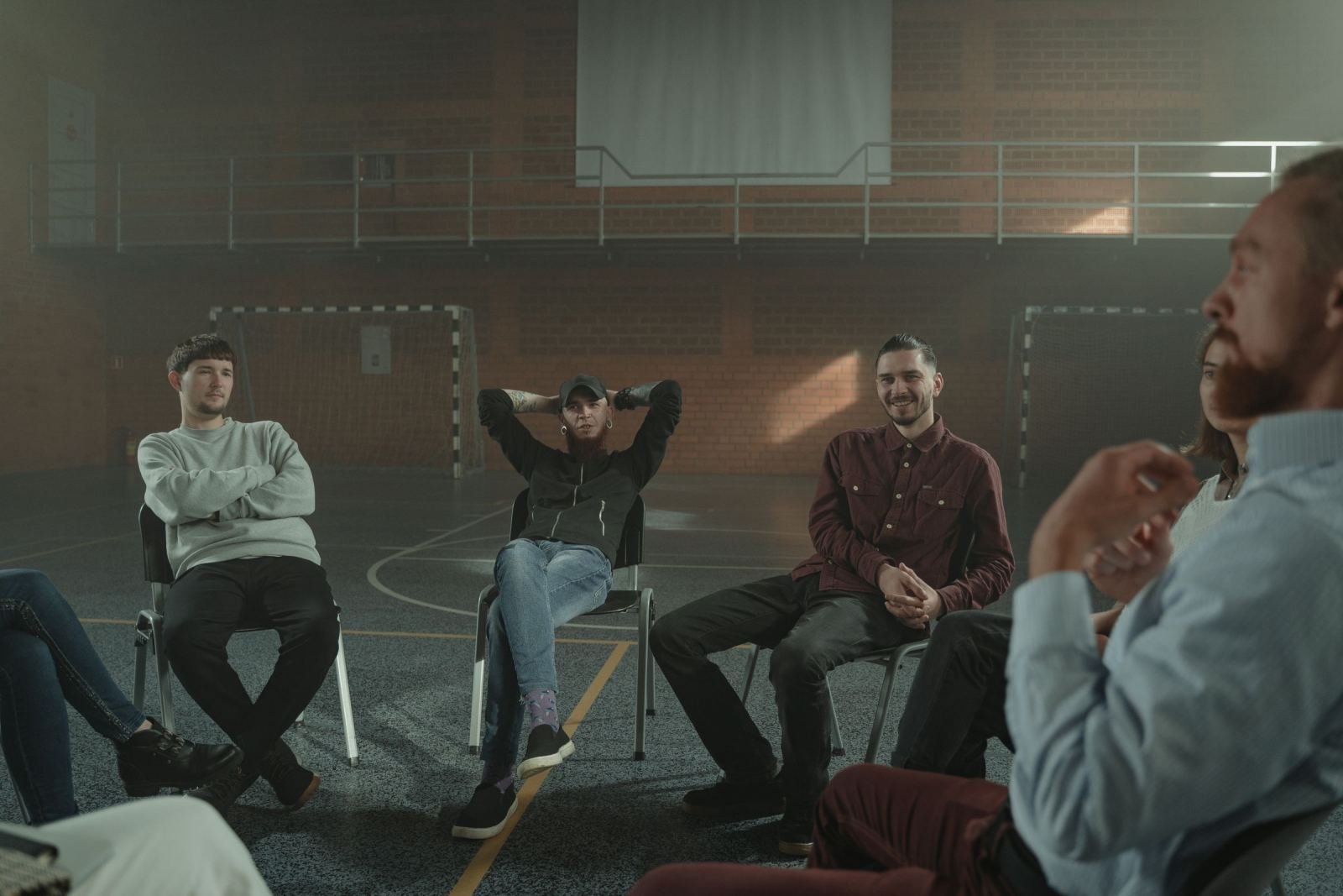 A group of people sitting in a circle of chairs in a large gym