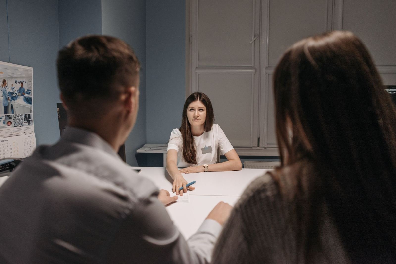 Two people talk to a staff member at a desk