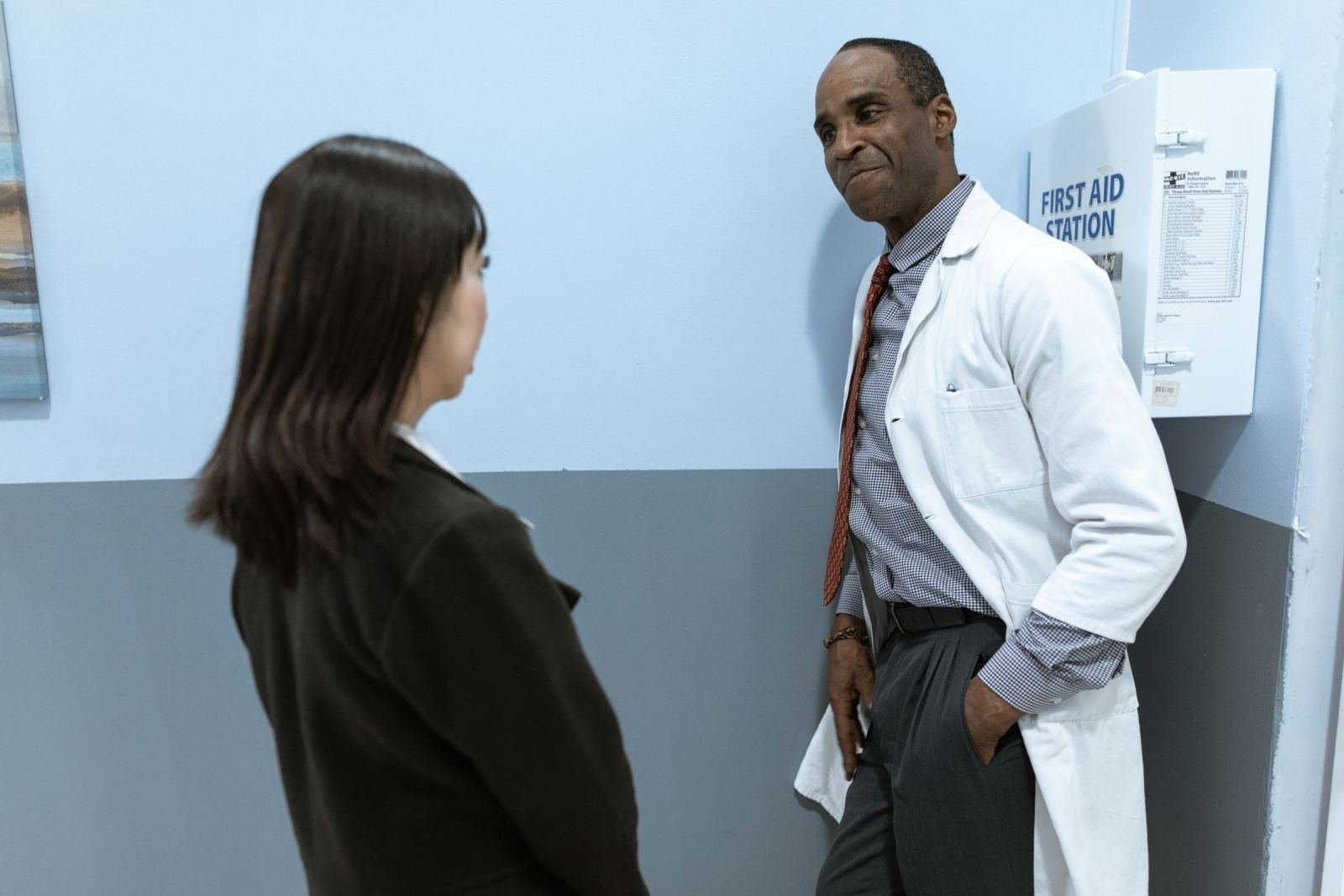 A doctor in a white coat chats with a patient in a clinic.