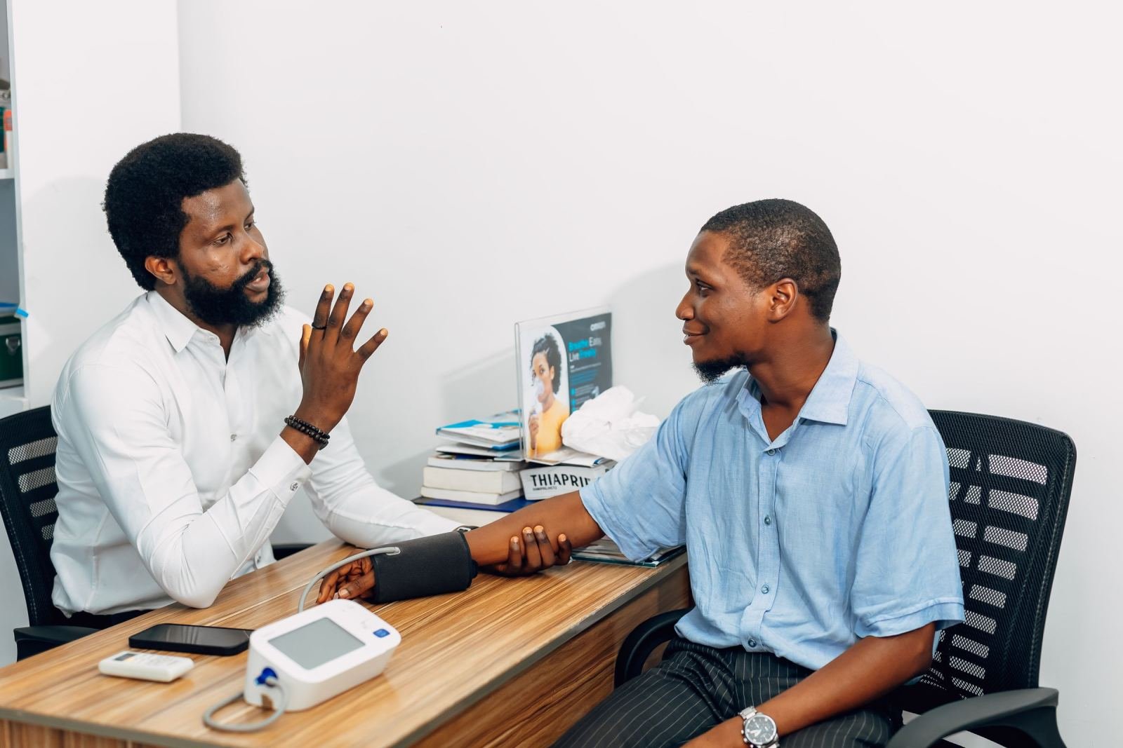 A healthcare provider speaks with a patient who has a blood pressure cuff on his arm