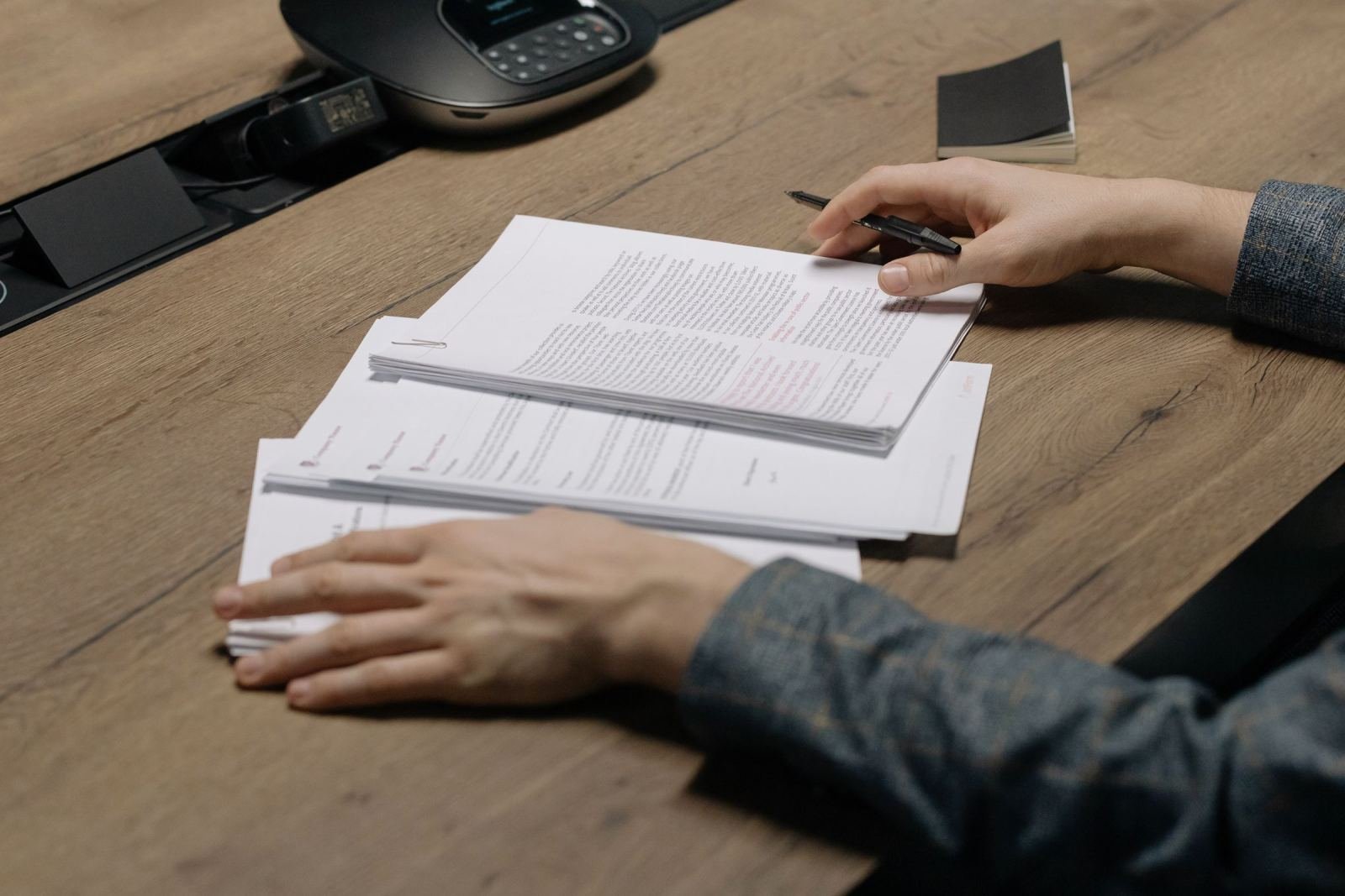 Two people review printed documents together at a wooden desk