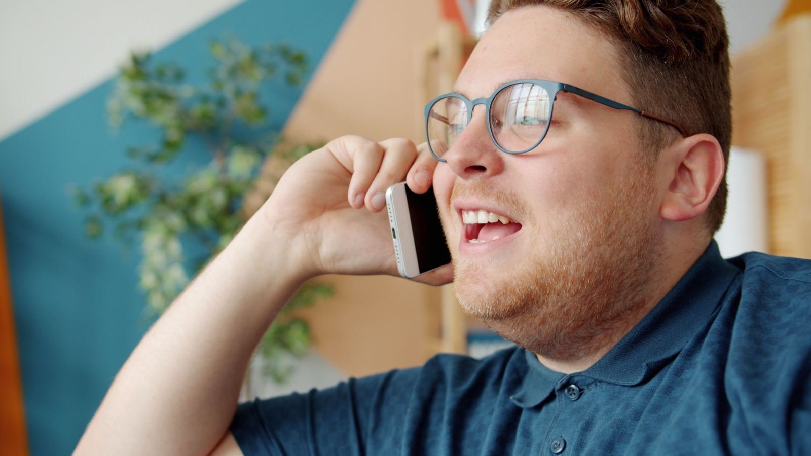 Man wearing glasses smiles while using his smartphone