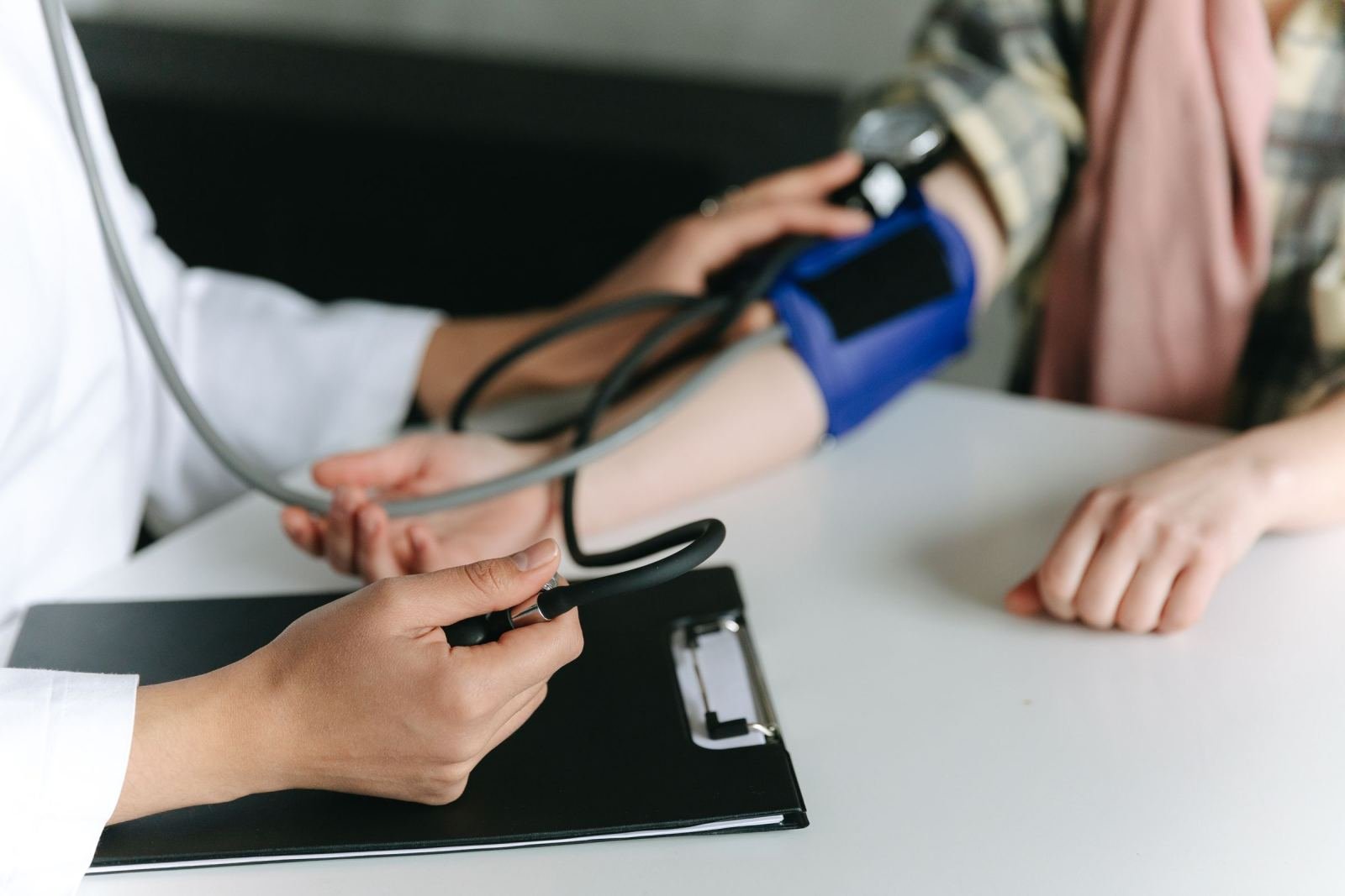 A healthcare provider checks a patient's blood pressure with a blue cuff