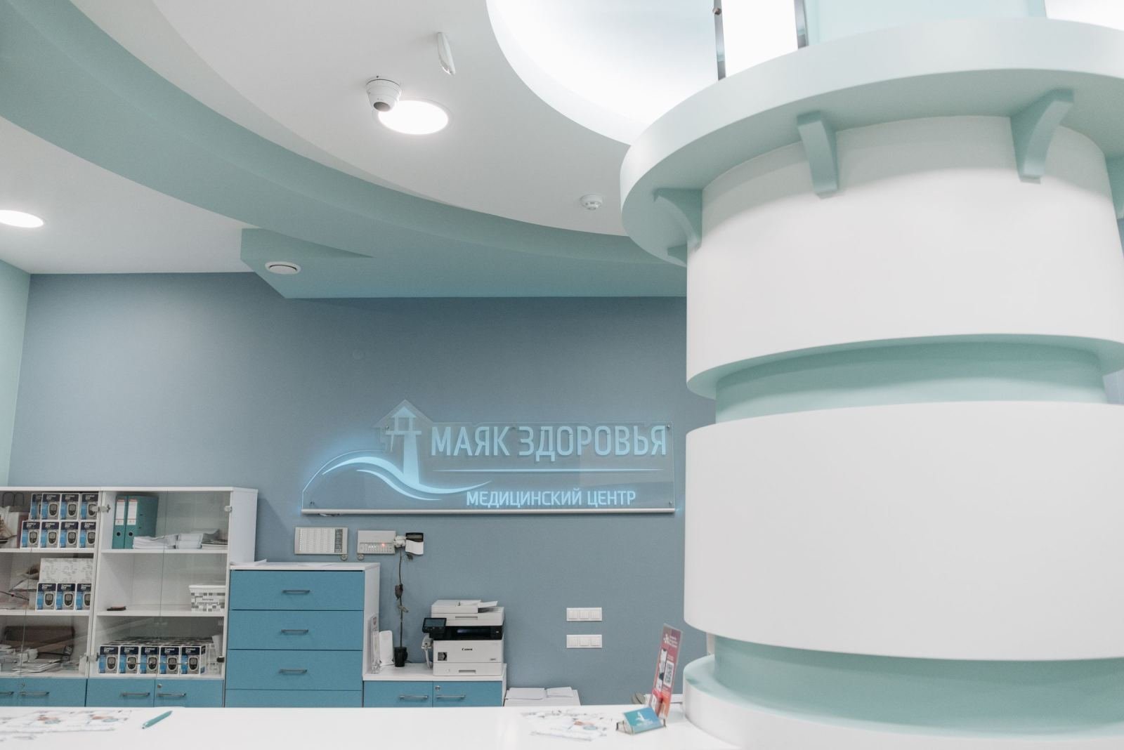 A bright, modern medical reception area with light blue walls and a white desk