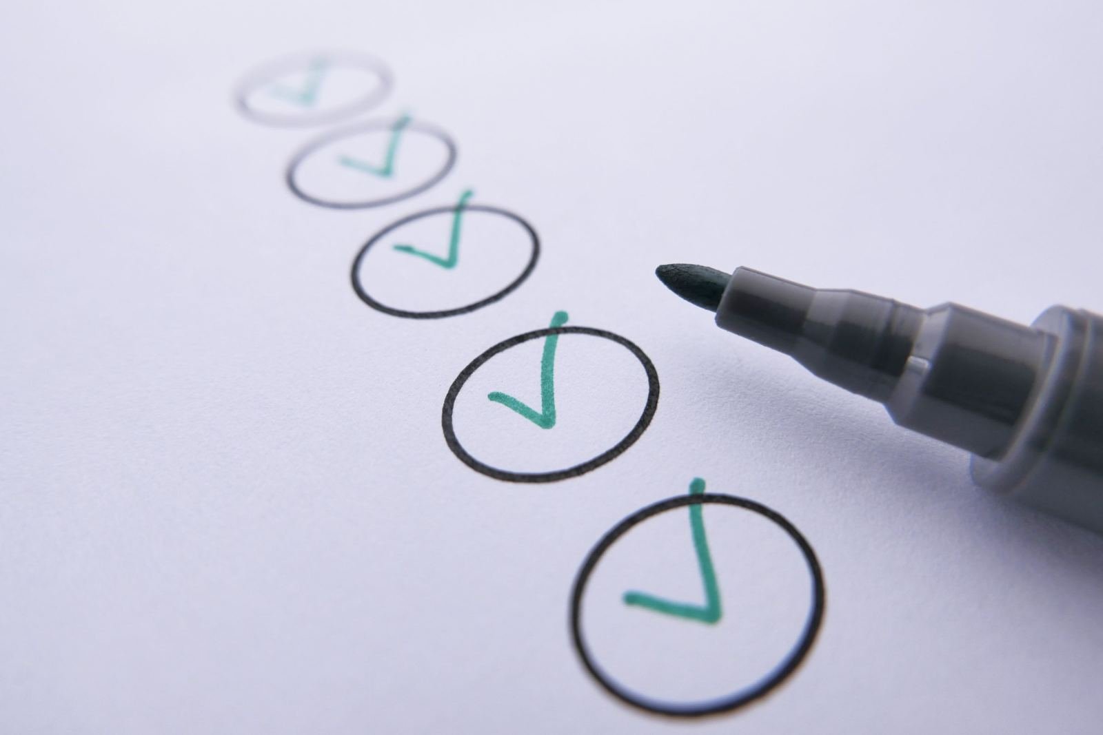 A grey marker next to a checklist with green check marks on white paper