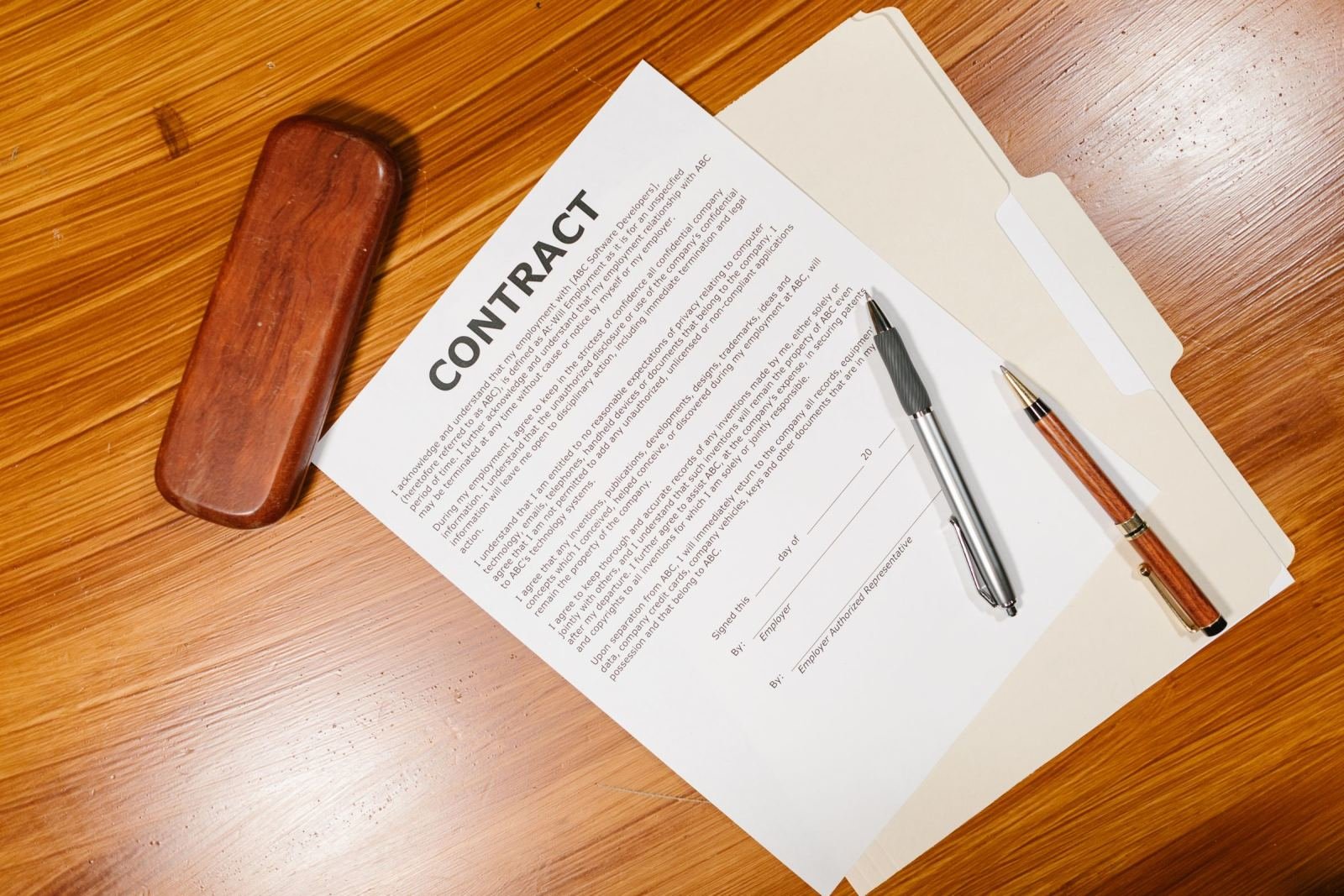 A printed contract, a pen, and a wooden stamp on a wooden table