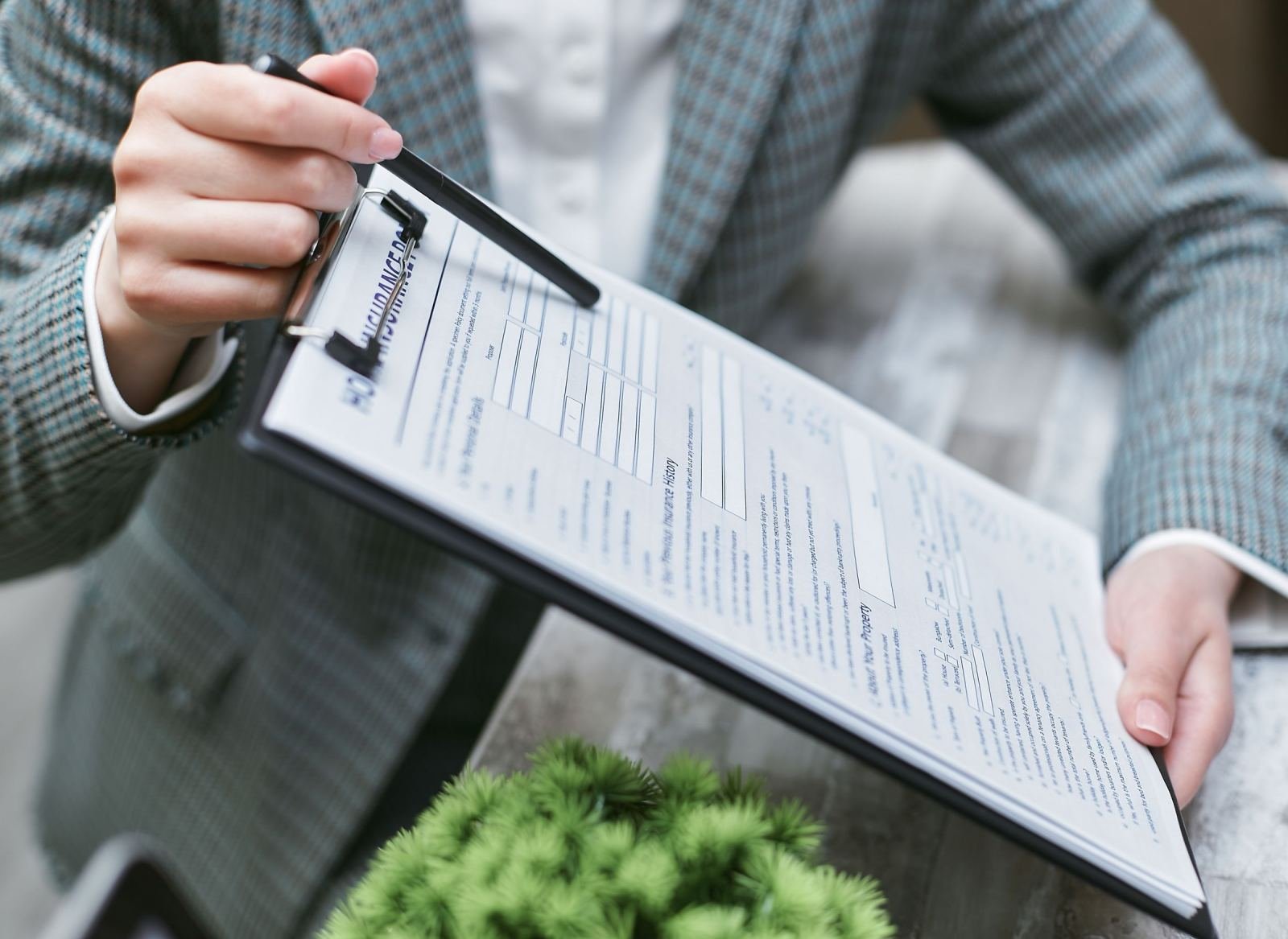 A person in a blazer holds a clipboard with an insurance form