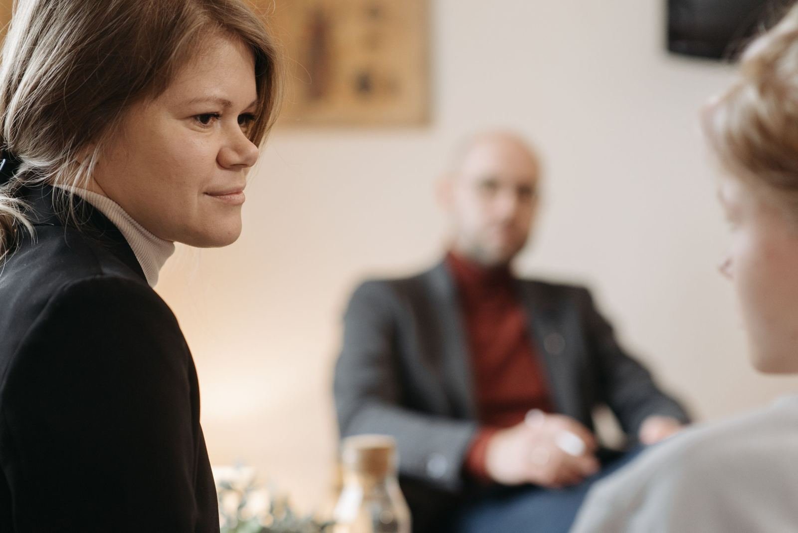 A woman in a blazer speaks with others in a quiet consultation room